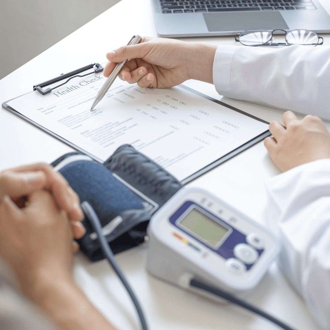 En la imagen se muestran un médico y un paciente, tomando la presión y anotando los resultados