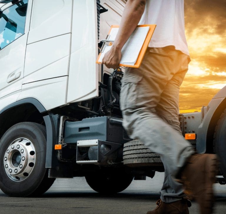 En la imagen se muestra un camionero inspeccionando un camión